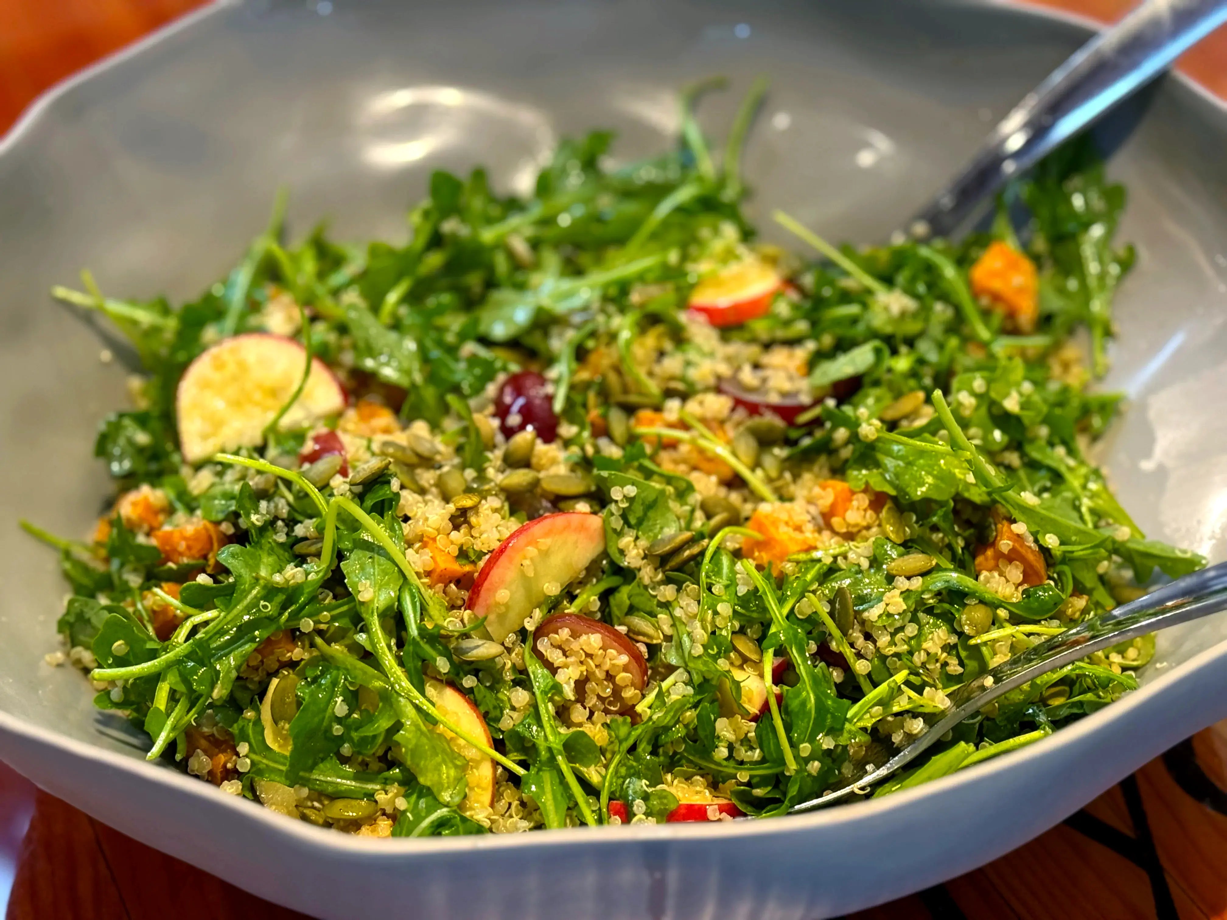 Large bowl of greens, grains and roasted vegetables being tossed