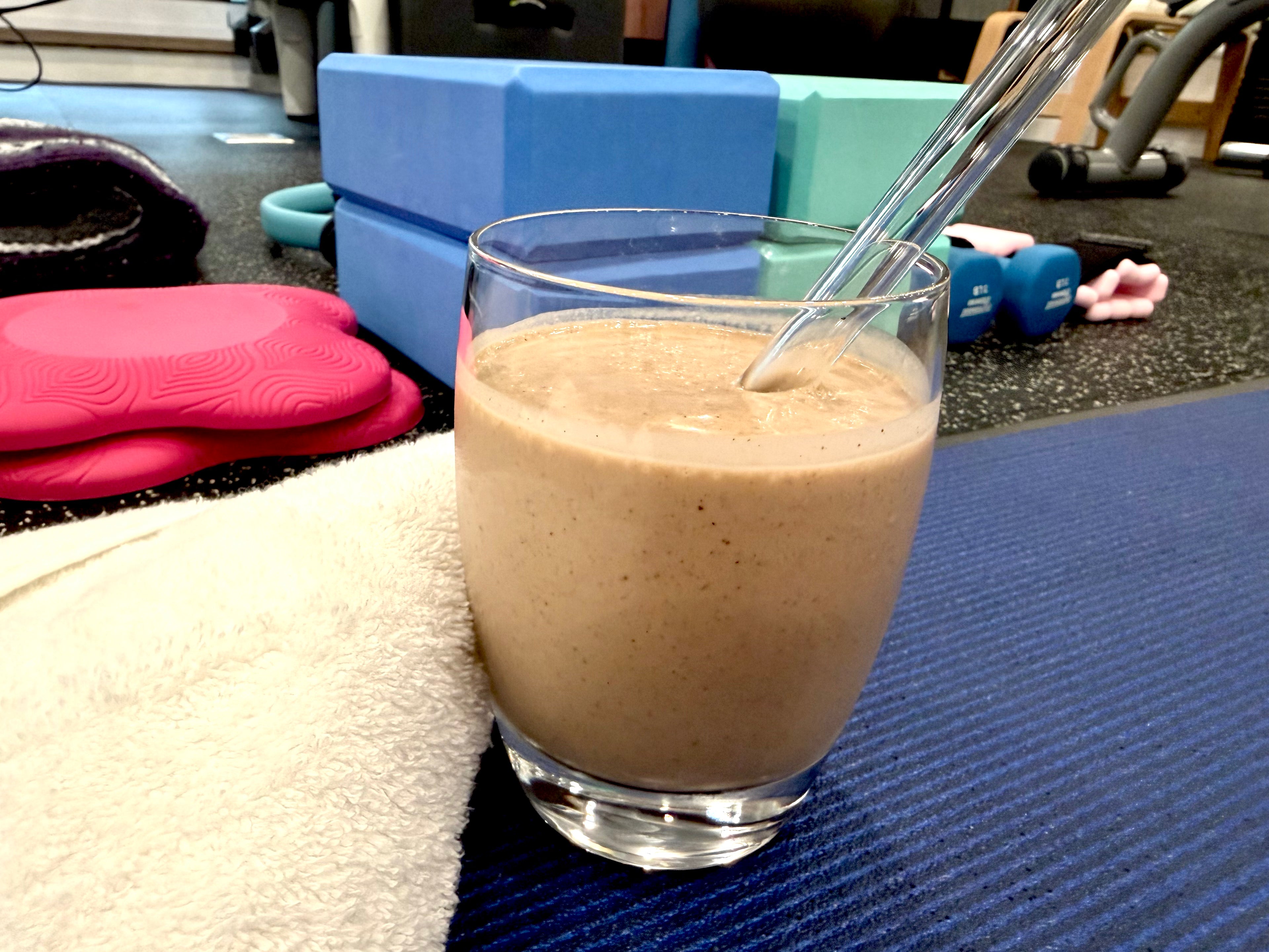 Glass of chocolate banana smoothie on a gym bench