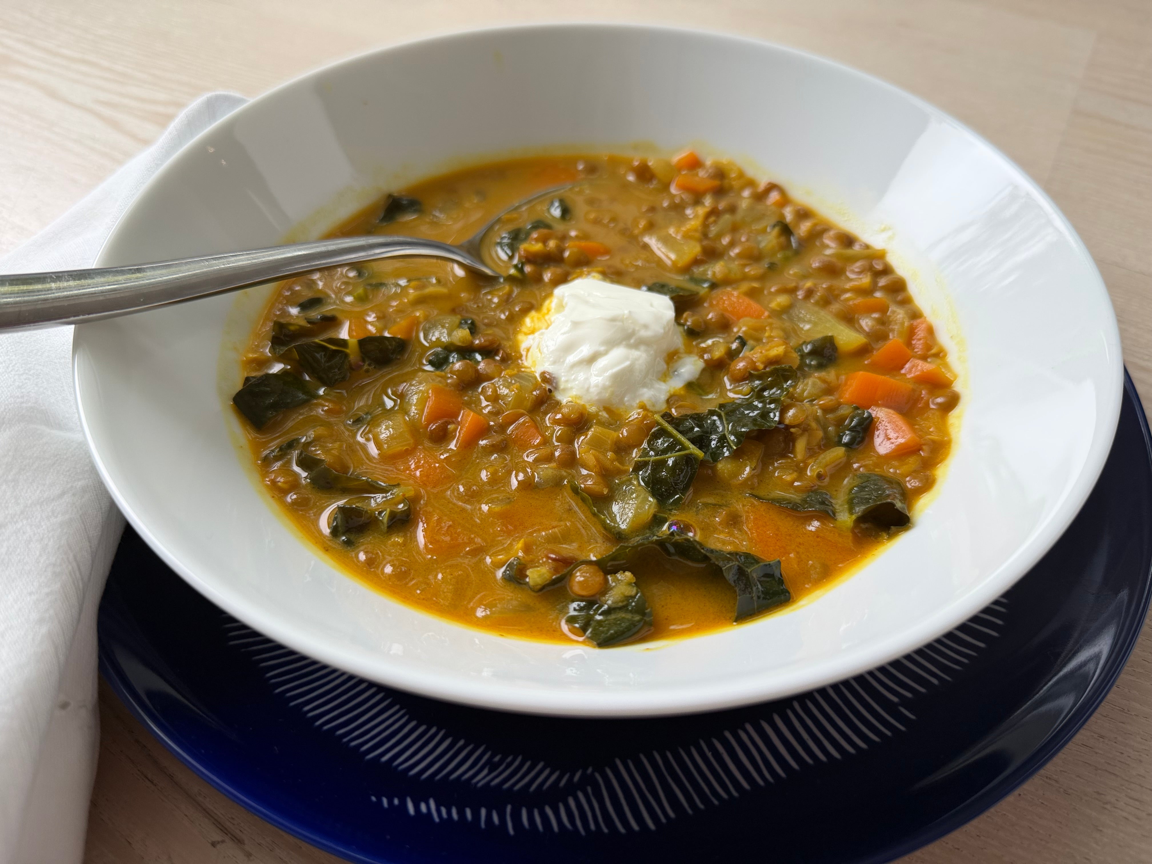 Bowl of lentil soup with greens and a dollop of yogurt