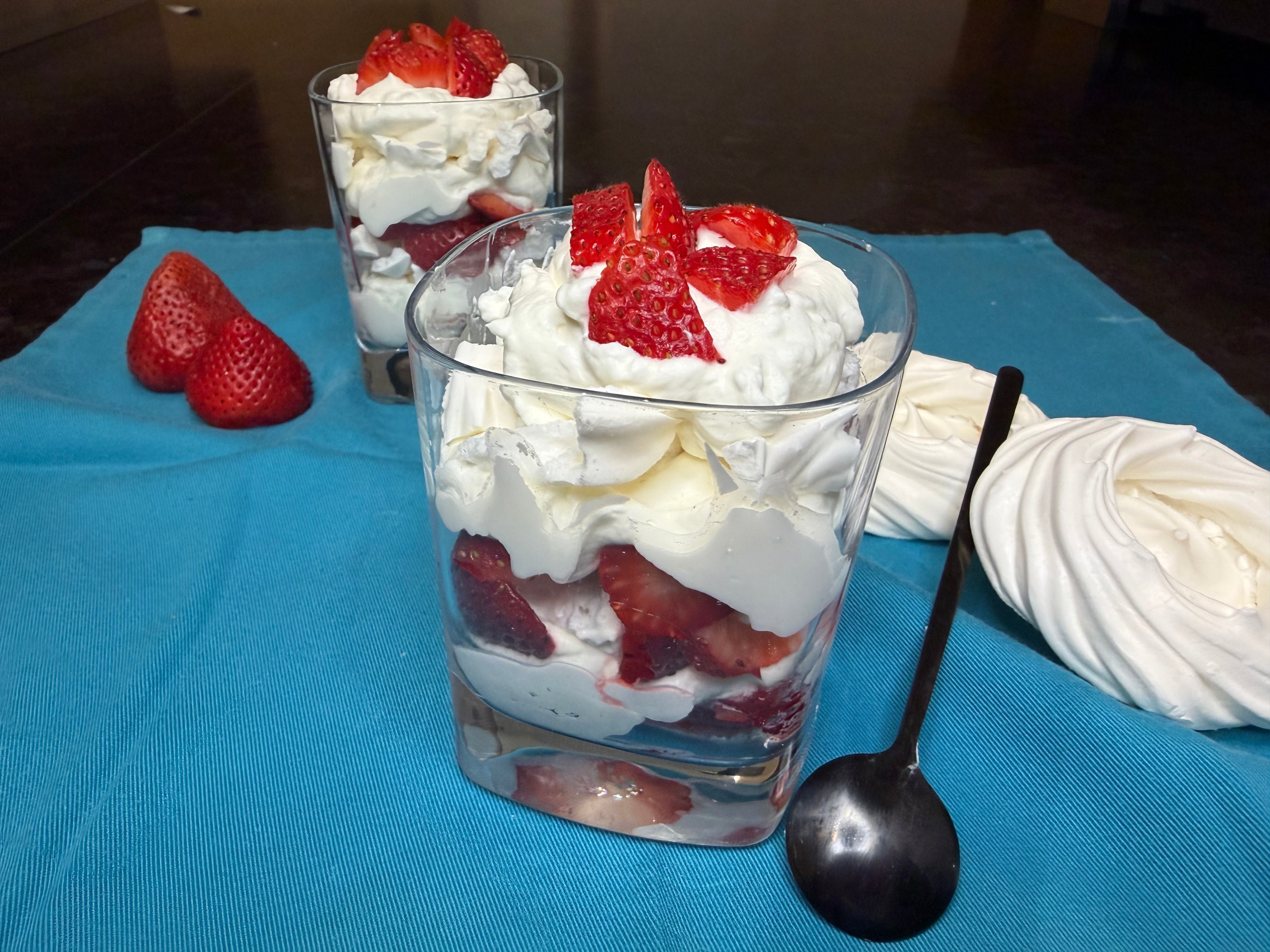 Glass of Eton mess with whipped cream, meringue and strawberries