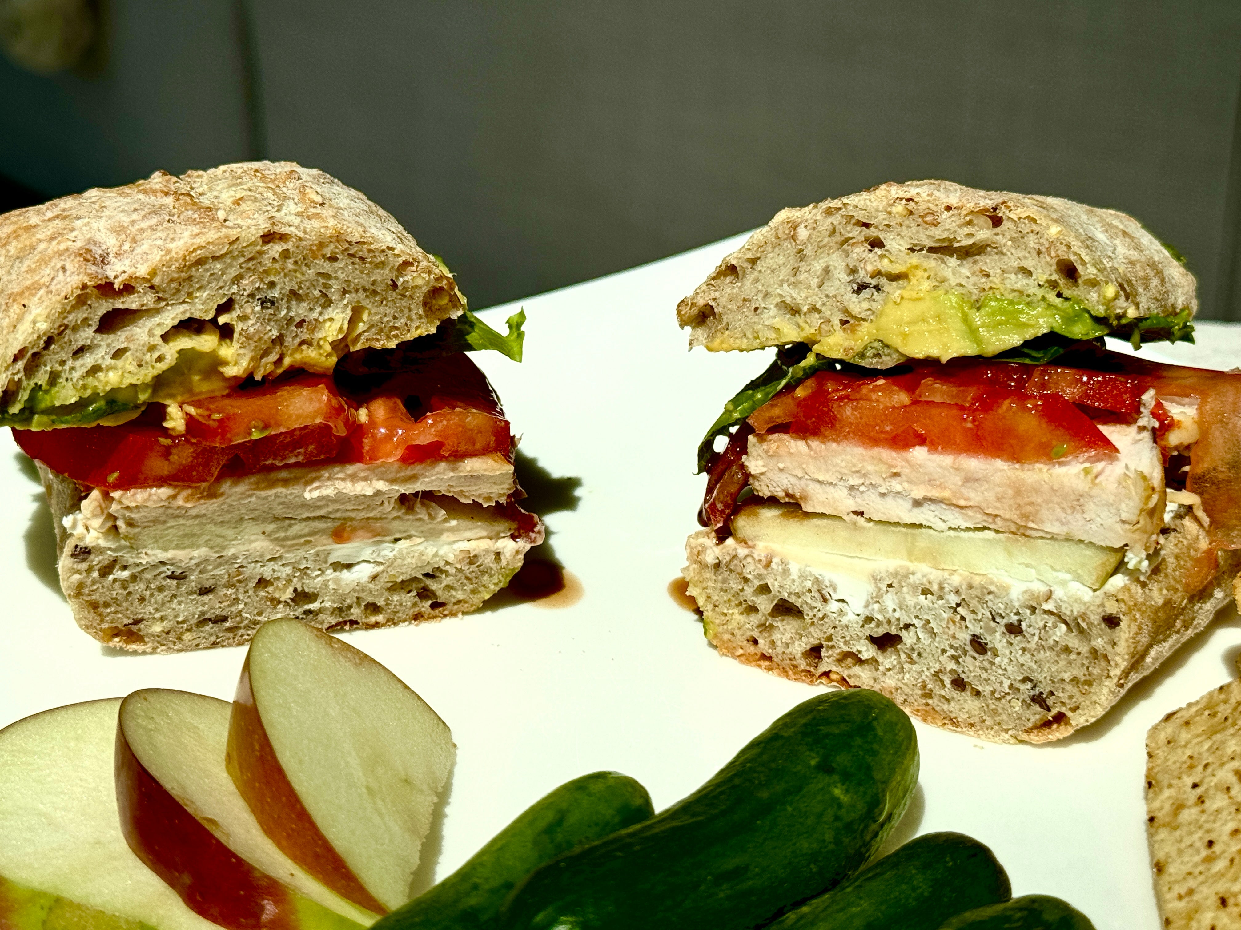 Chicken sandwich cut in half with apple slices on the side